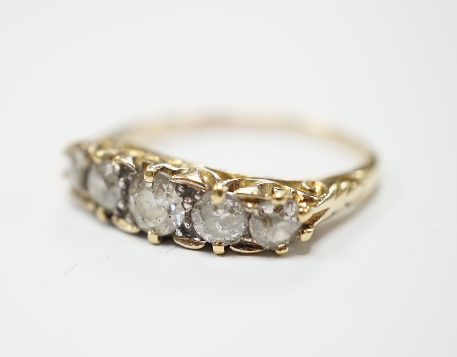 A yellow metal and graduated five stone diamond set half hoop ring, size Q, gross weight 3.9 grams.